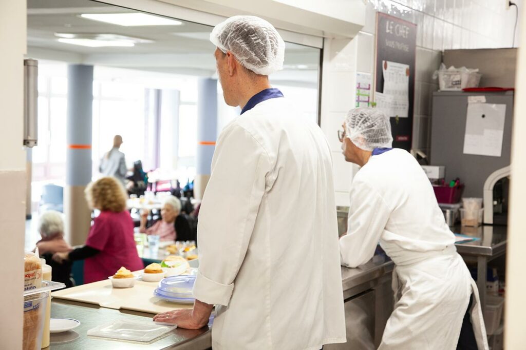 Les cuisiniers de l’EHPAD Les Cannes Blanches passent des plats préparés sur place à l’équipe de restauration pour le service des résidents.
